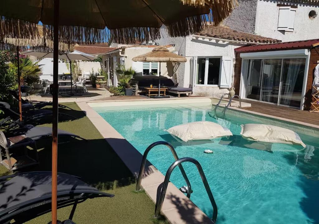 - une piscine avec un parasol à côté d'une maison dans l'établissement Tropical Spirit House, à Marignane