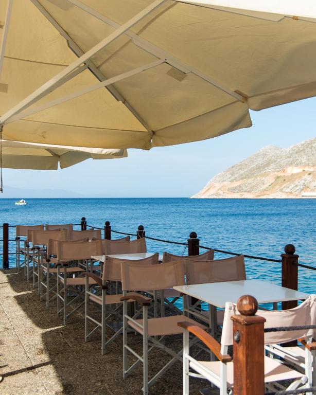 a row of tables and chairs next to the ocean at Nireus Hotel in Symi