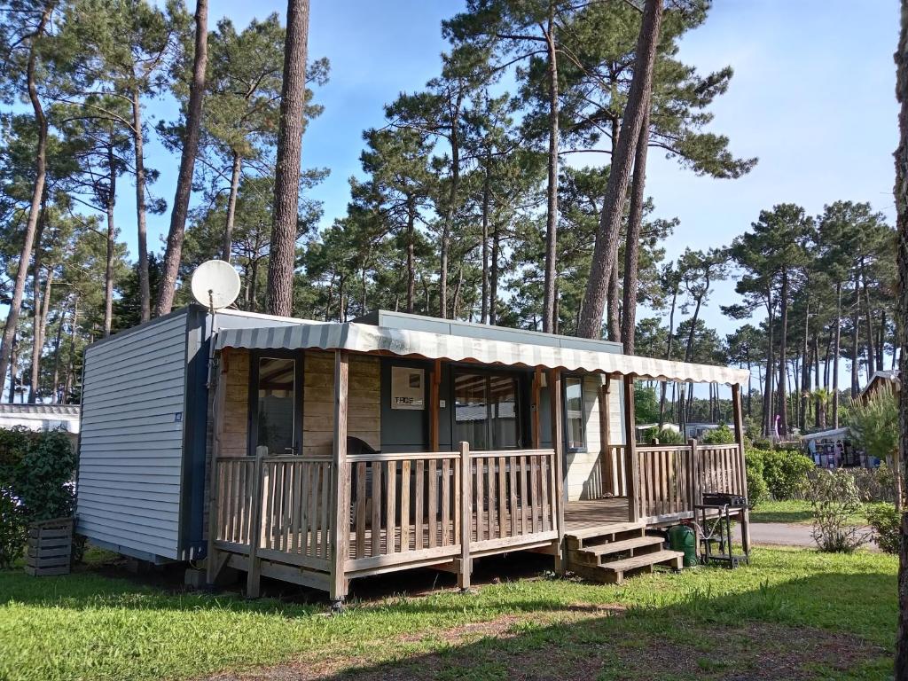 a tiny house with a porch and two benches at MH 462 Les dunes de Contis 2 chambres et 2 salles de bains dans camping 4 étoiles in Saint-Julien-en-Born