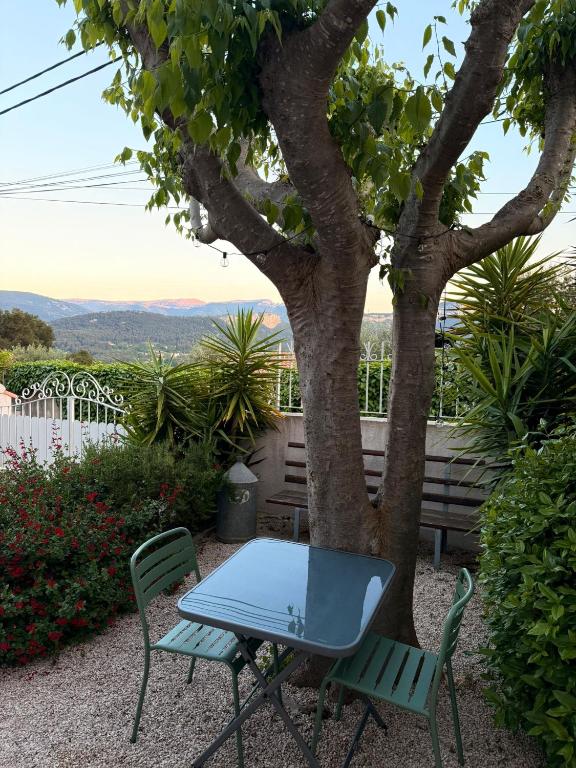 a table and chairs sitting next to a tree at Le Micocoulier in Auriol