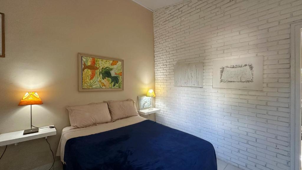 a bedroom with a blue bed and a white brick wall at Casa confortavel, bem equipada com Wi-Fi e garagem in Massaguassu