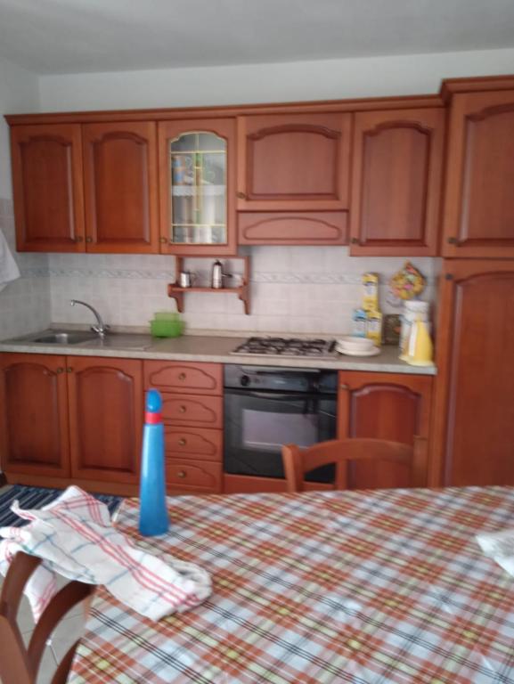 a kitchen with wooden cabinets and a table with a table cloth at Lungomare 2 in Porto Alabe