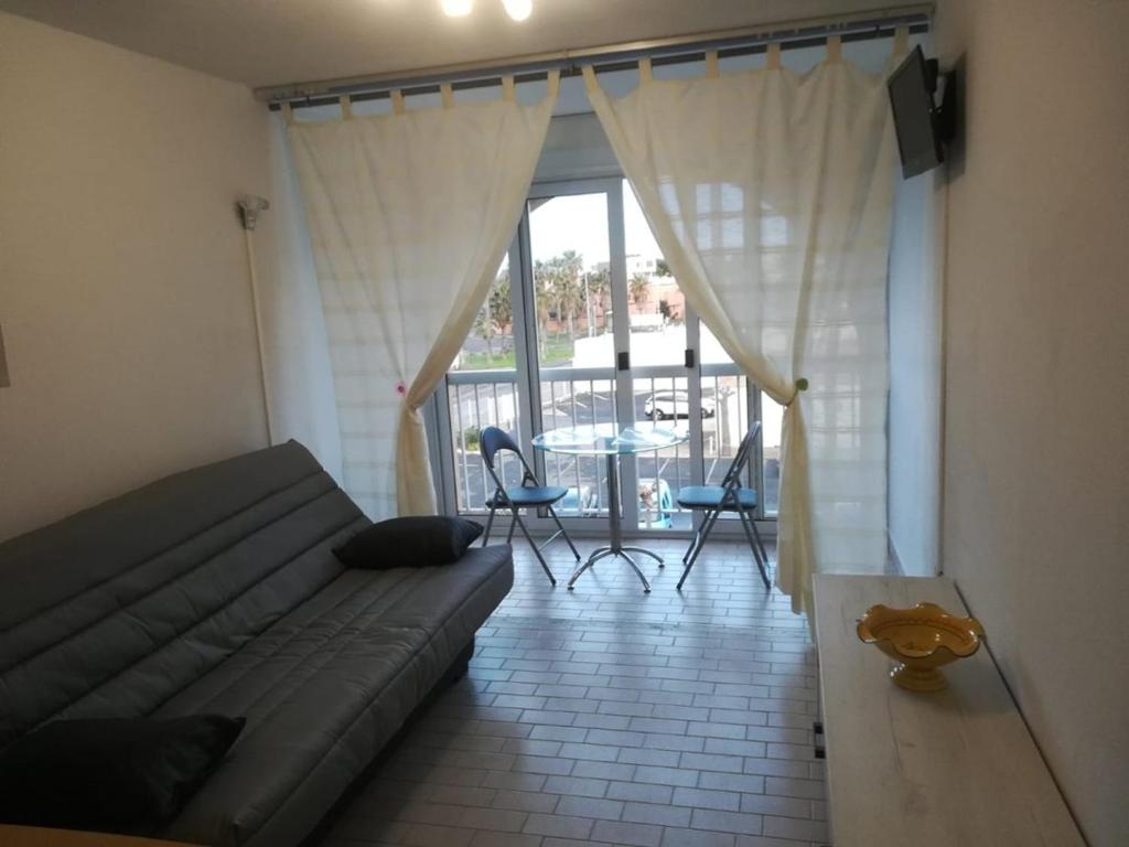 un salon avec un canapé et une table avec des chaises dans l'établissement Studio Port Soleil PS580 - 2 personnes, au Cap d'Agde