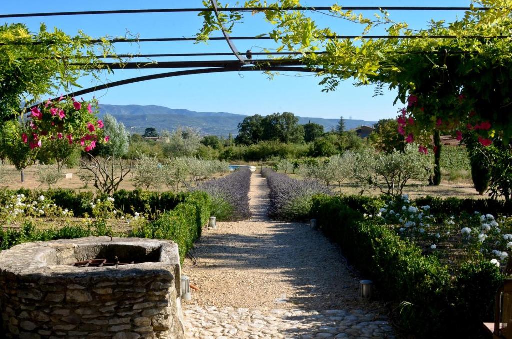 un chemin à travers un jardin avec des fleurs et une arche dans l'établissement Bastidon Silvestre, à Saint-Saturnin-lès-Apt