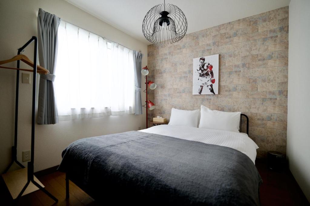 a bedroom with a large bed and a brick wall at DAC Susukino in Sapporo