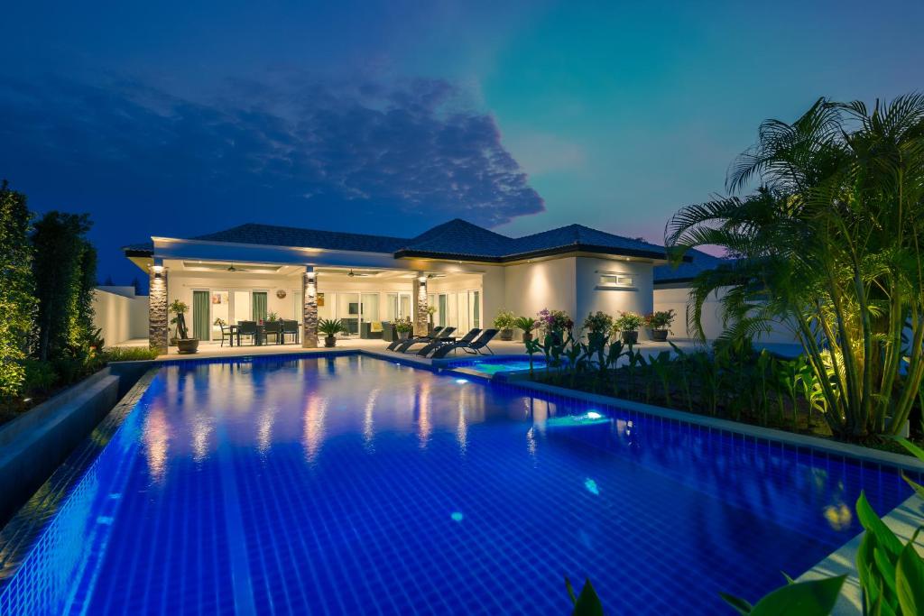 a swimming pool in front of a house at night at Orchid Paradise Homes Villa in Hua Hin