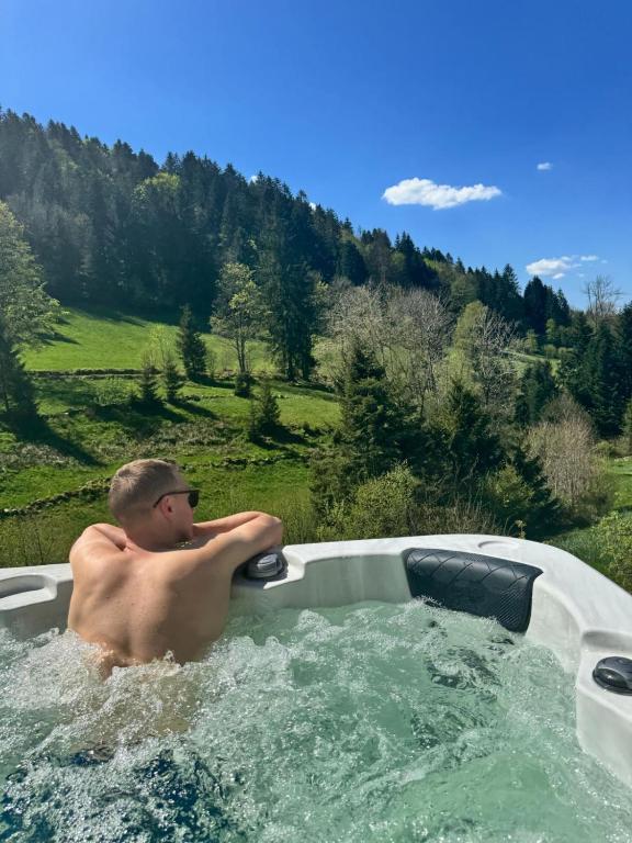 Un homme dans un jacuzzi dans un champ dans l'établissement Le Petit Paradis, Spa-Sauna and Gym, à Gérardmer