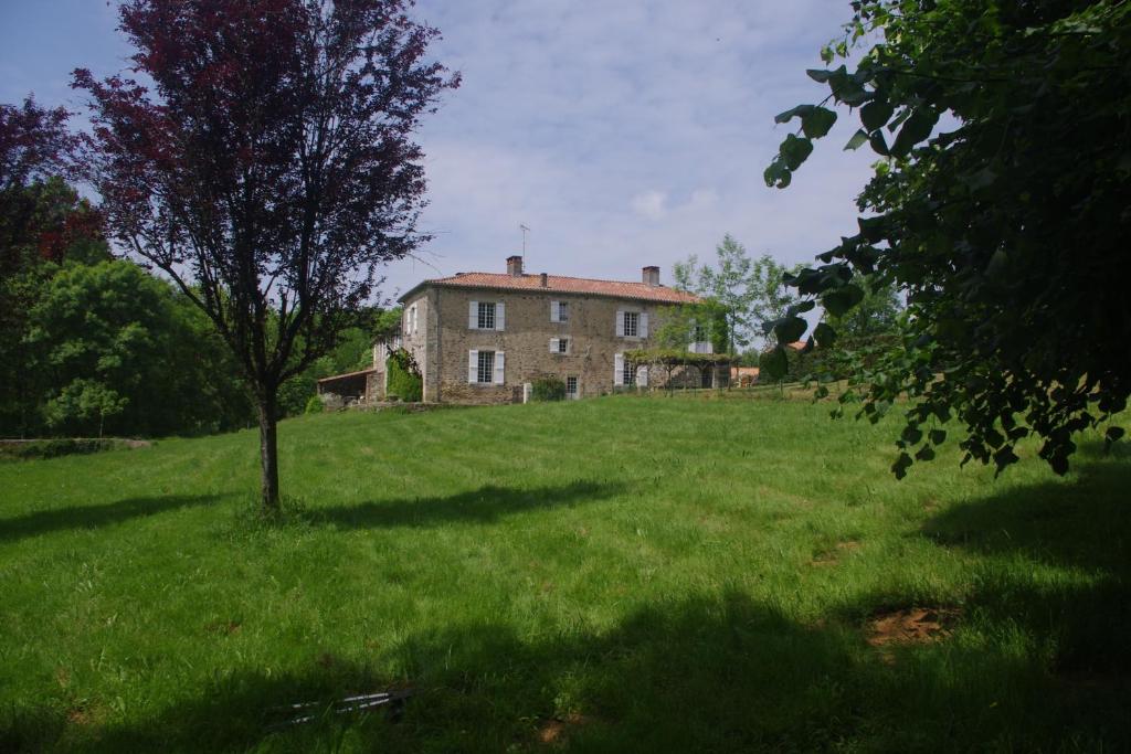 une vieille maison dans un champ avec un arbre dans l'établissement Logis Vendéen 10-12 personnes. piscine et parc., à La Jaudonnière