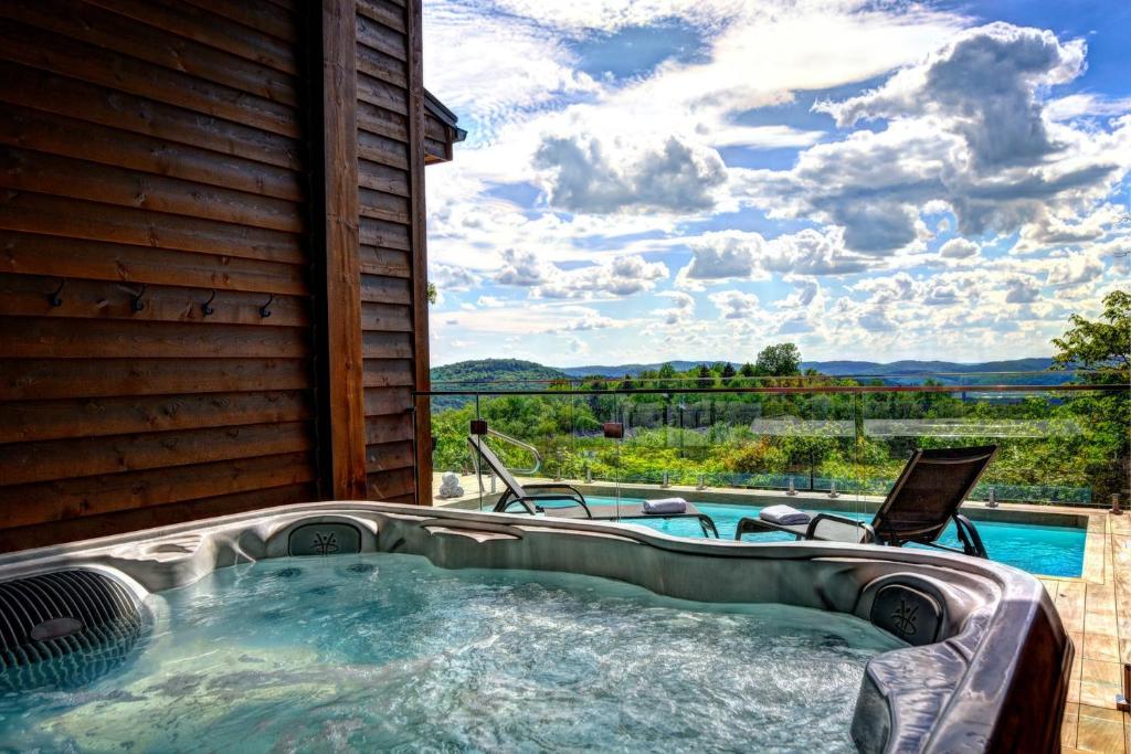 a jacuzzi tub with two chairs and a view at NEW! Villa Panorama 4 Seasons Heated Pool Hot Tub in Mont-Tremblant