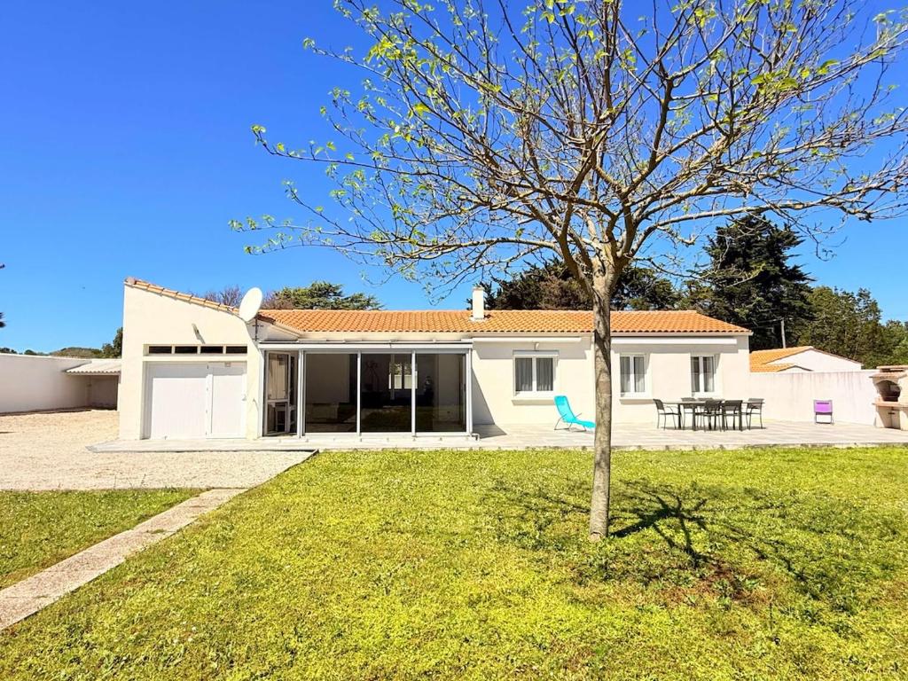 a white house with a tree in the yard at La maison des suisses in Saint-Denis-dʼOléron