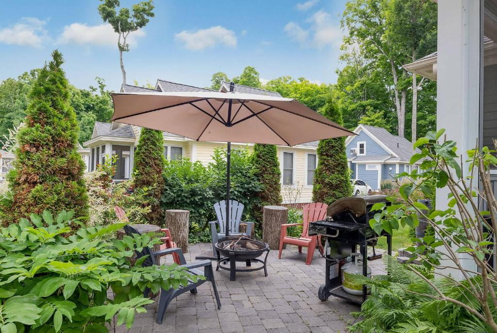 een patio met een parasol, een grill en stoelen bij The Cardinal - 7 Hollow in Cherry Valley