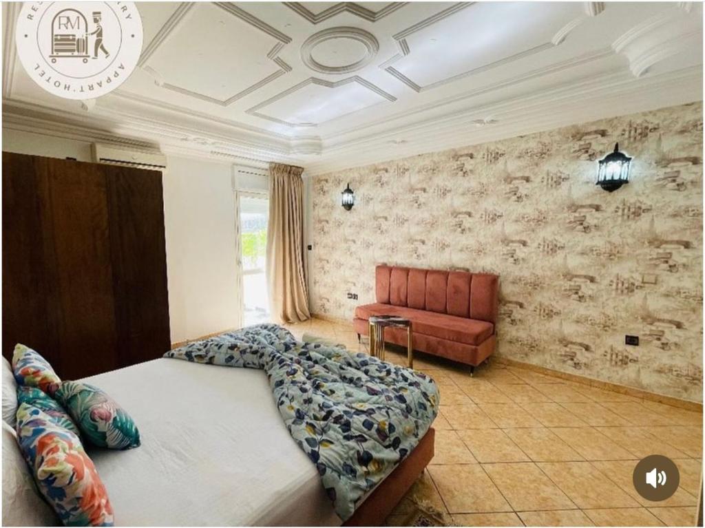 a bedroom with a large bed and a red couch at Hotel Merry in Agadir