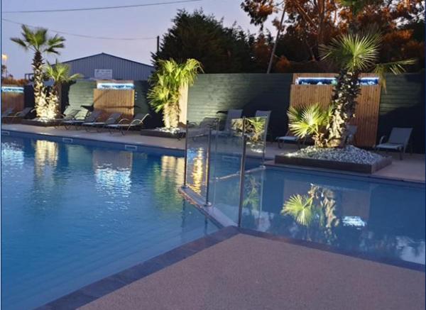 - une piscine bordée de chaises et de palmiers dans l'établissement Mobil-home l'évasion, à La Bernerie-en-Retz