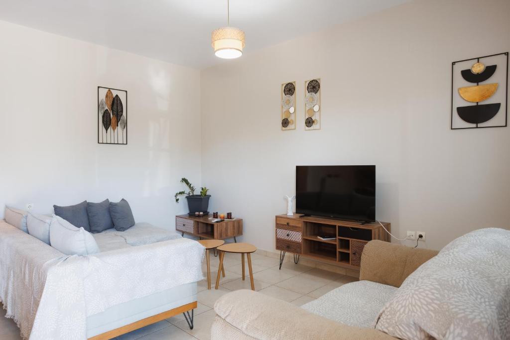 a living room with a couch and a tv at K & M Retreat - Detatched, 2 Bedroom, 3 AC, Stunning Hill Views in Evropoúloi