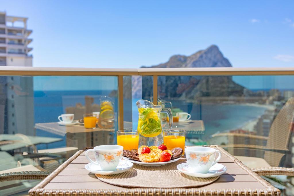 una mesa con un plato de fruta y zumo en el balcón en Apartment of Joy Piscina Aparcamiento, en Calpe