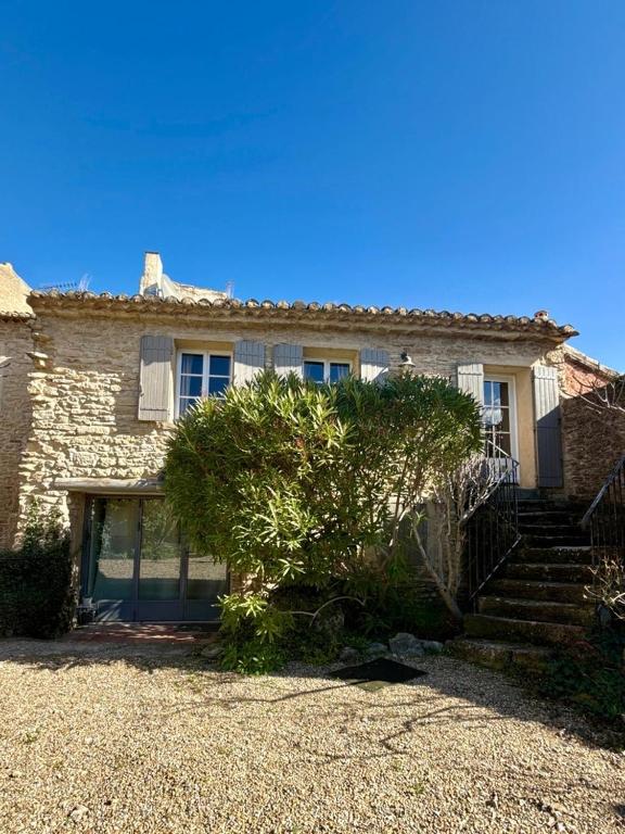 une maison en pierre avec des escaliers et un arbre devant dans l'établissement Le Mas de Cabrières, à Cabrières-dʼAvignon