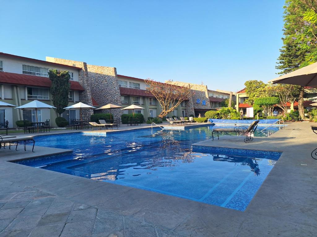 a large swimming pool in a hotel with tables and umbrellas at Hotel Real de Minas Tradicional in Querétaro