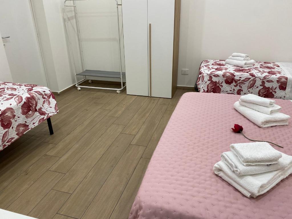 a room with two beds with towels and a pink rug at Il Tulipano house in Catania