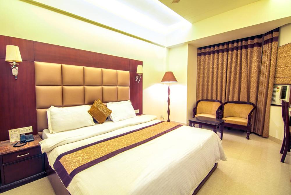 a hotel room with a large bed and a chair at Hotel Abhinandan in Mathura