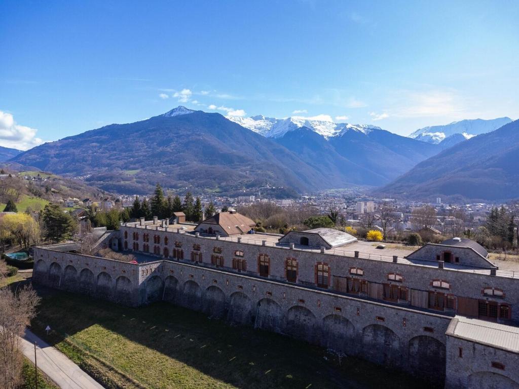ein altes Gebäude mit schneebedeckten Bergen im Hintergrund in der Unterkunft Le Château Fort 16 in Albertville