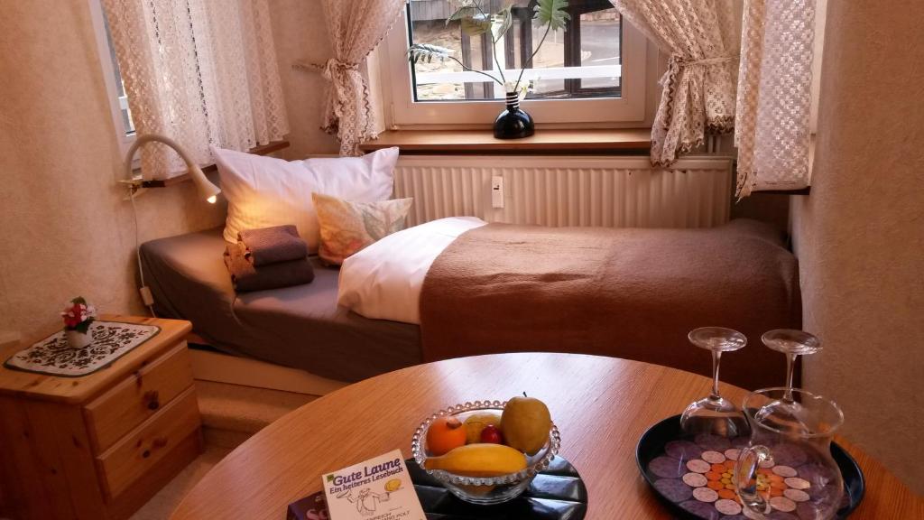 ブラウンラーゲにあるUrlaubsOase Braunlageのベッド1台、テーブル(フルーツボウル付)が備わる小さな客室です。