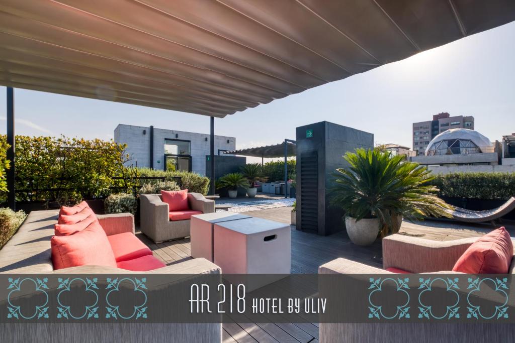 Un patio con sofás y mesas en una azotea. en AR 218 Hotel by ULIV, en Ciudad de México