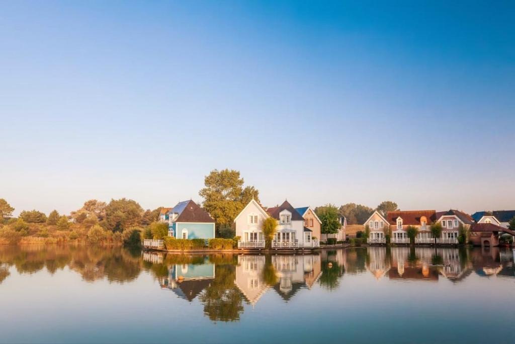a group of houses sitting on a lake at Le Cottage de Belle Dune in Fort-Mahon-Plage