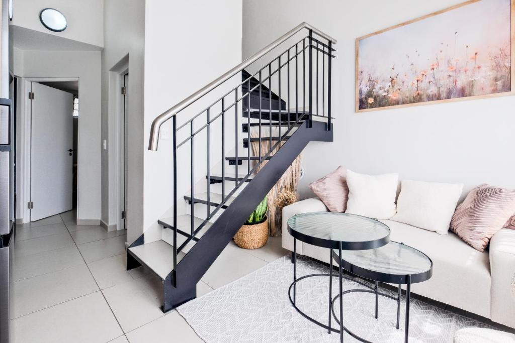 Una sala de estar con una escalera y un sofá. en Peaceful Fourways Loft Apartment, en Sandton