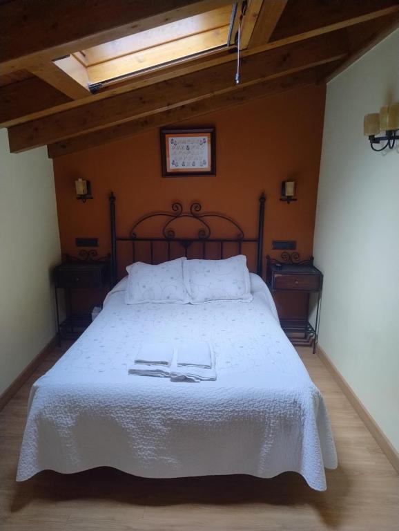 a bedroom with a large bed with white sheets and a clock at CASA ANGELITA INTRIAGO CANGAS DE ONis in Cangas de Onís