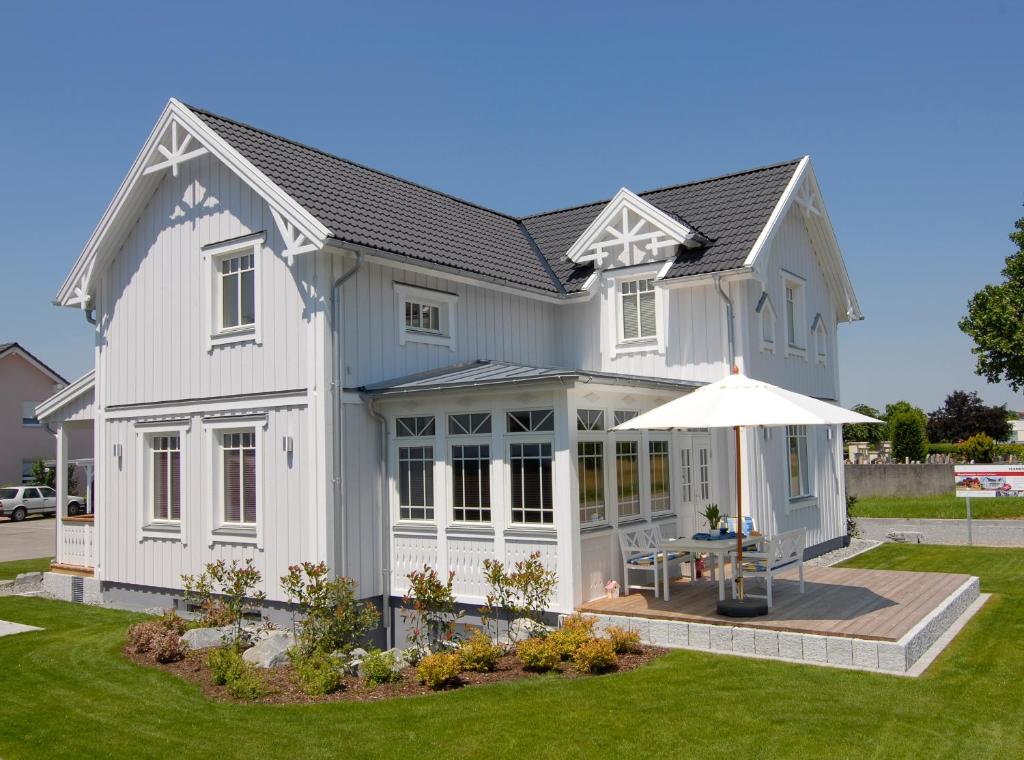 une maison blanche avec un parasol dans la cour dans l'établissement Villa Scandic Apartments, à Rust