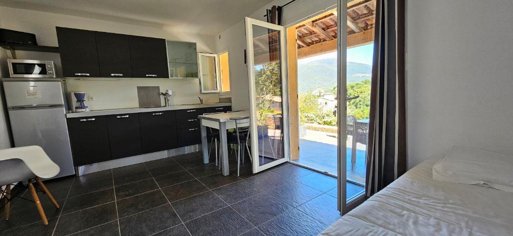 eine Küche mit schwarzen Schränken und Blick auf einen Balkon in der Unterkunft Studio Dolce & Vita C2 vue mer avec piscine in Propriano