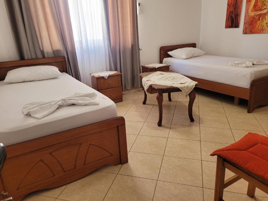 a room with two beds and a table in it at Geri Apartment in Ksamil