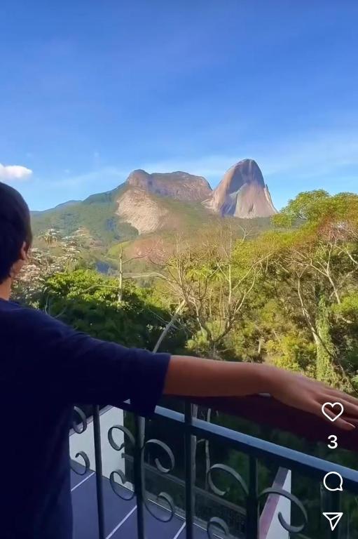 a man standing on a balcony looking out at a mountain at VISTA AZUL Prime in Domingos Martins