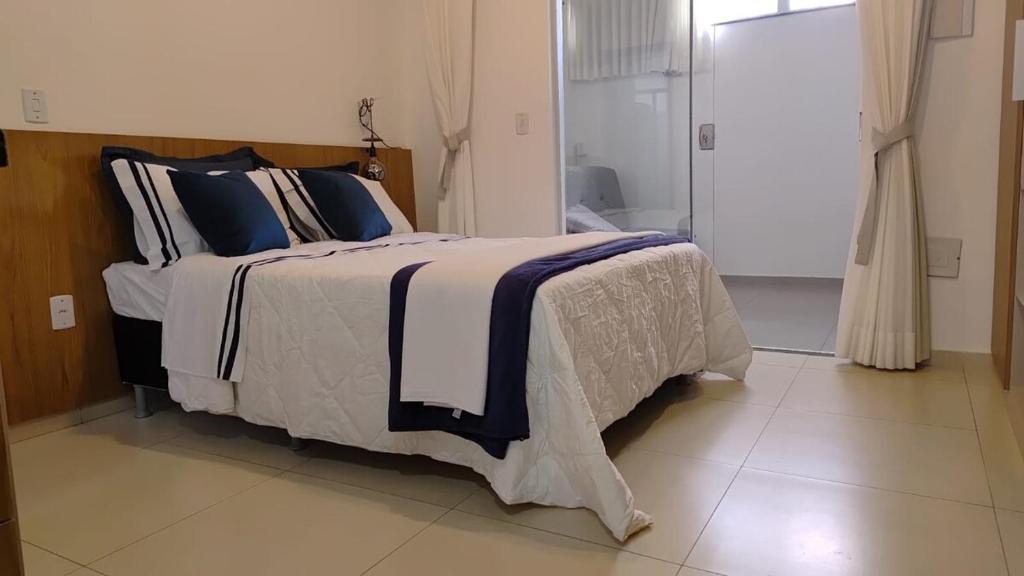 una camera da letto con un grande letto con cuscini blu e bianchi di Studio 101, a 3 km da UFV vaga gratis a Viçosa