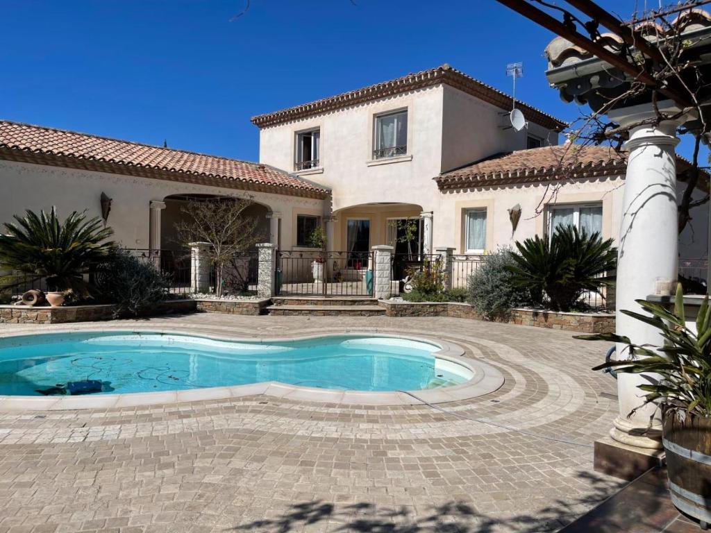 a swimming pool in front of a house at Villa Le Rossignol in Puimisson