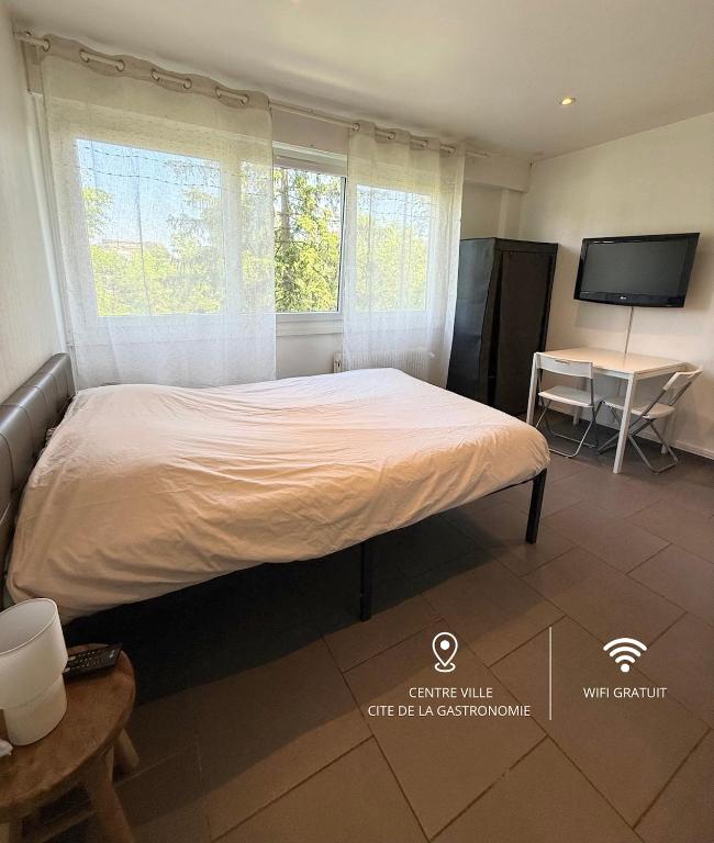 une chambre avec un lit, une table et une télévision dans l'établissement Studio tout confort cité de la gastronomie (3), à Dijon