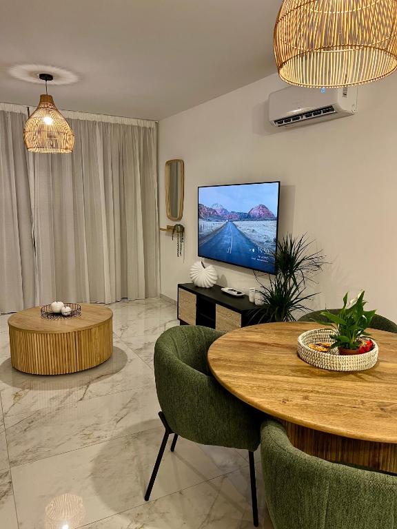 a living room with a television and a table and chairs at FatCow Beach Apartment Ultra in Larnaca