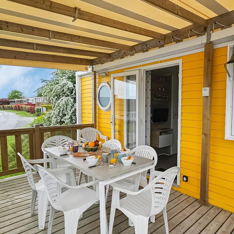 une table et des chaises sur une terrasse avec une maison jaune dans l'établissement ohana, à Litteau