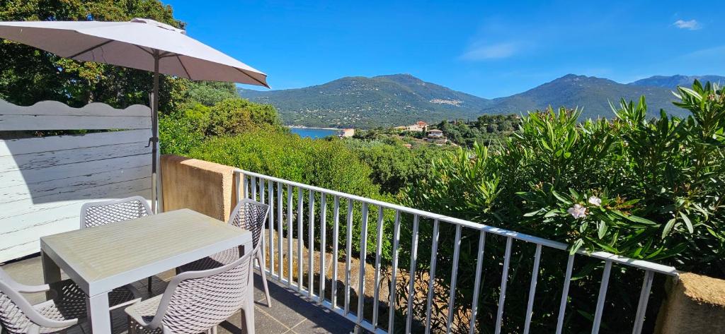 une table et des chaises sur un balcon avec un parasol dans l'établissement Studio Dolce & Vita D1, vue mer et Piscine, à Propriano