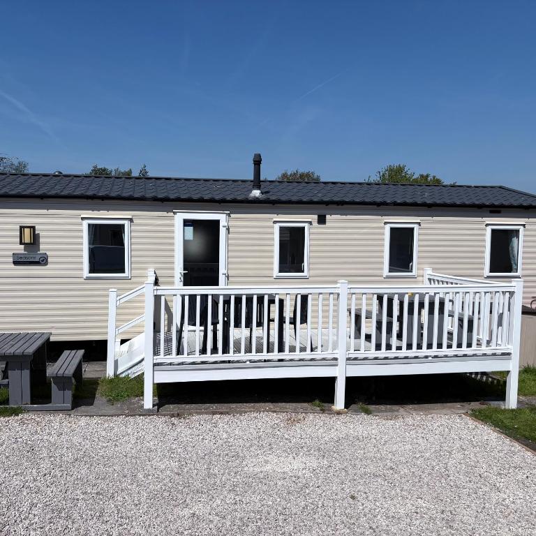 a white house with a porch and a white fence at McCanns Caravan Marton Mere in Blackpool