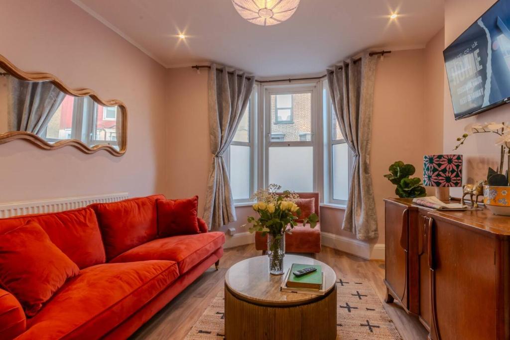 マーゲイトにあるCosy Margate Getaway, Sleeps 5 By Adlivの赤いソファとテーブルのあるリビングルーム