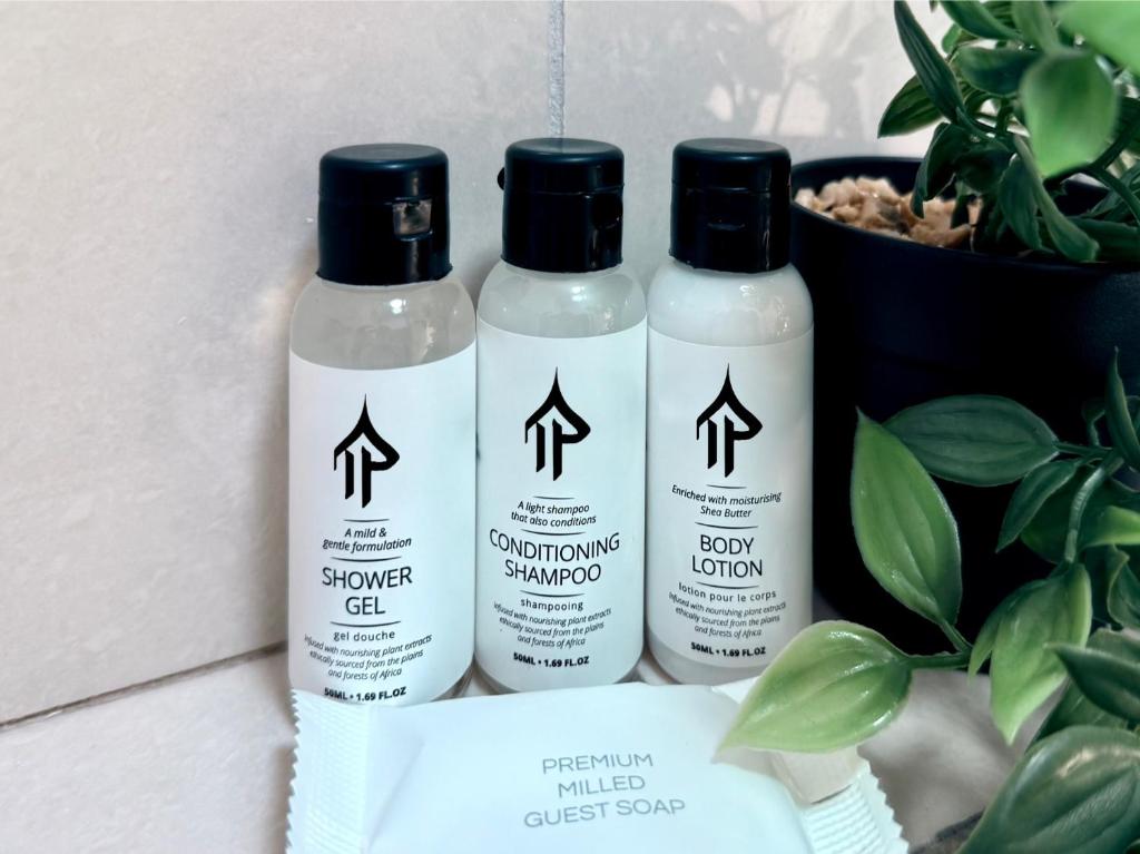 three bottles of shower gel sitting next to a plant at Cosy Urban Apartment in Durban