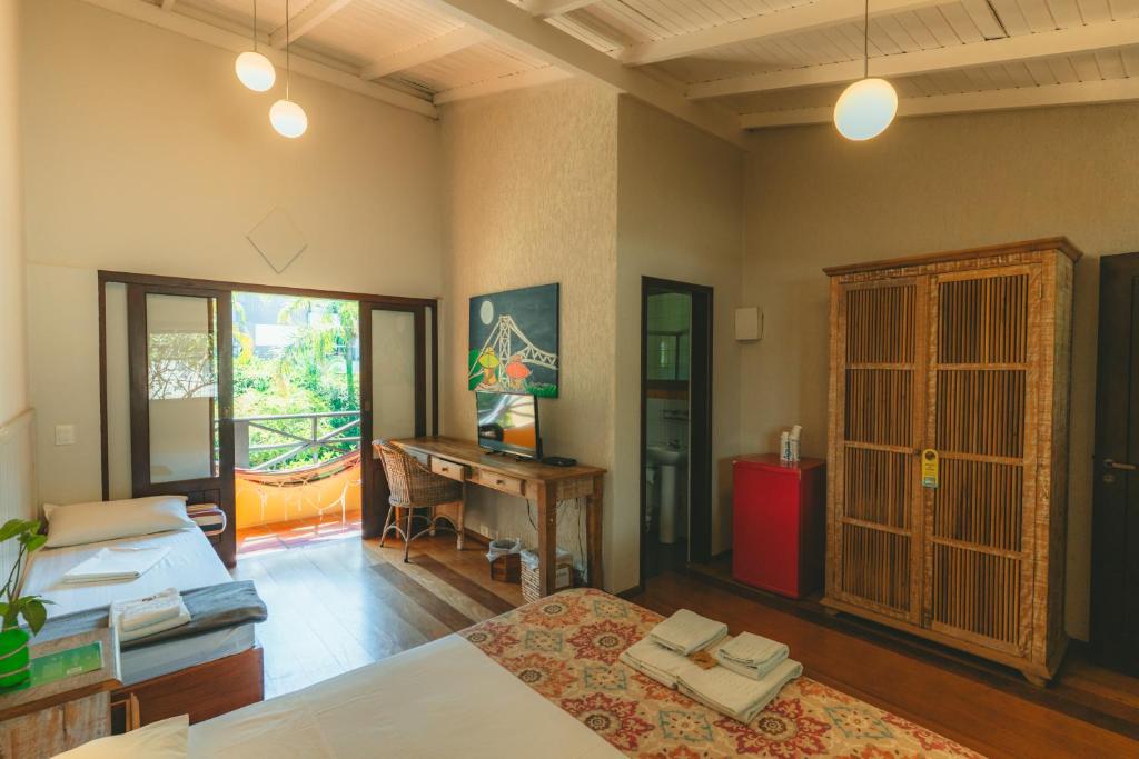 a room with a bed and a desk and a table at Pousada Vila Tamarindo Eco Lodge in Florianópolis