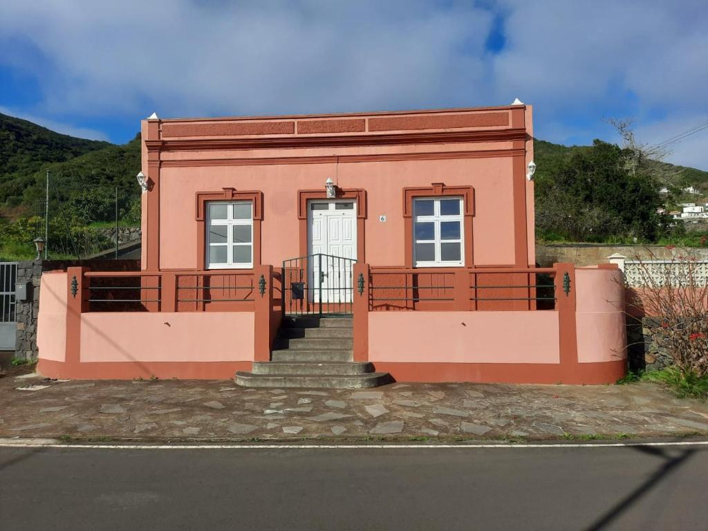 Una pequeña casa rosa con escaleras y una puerta. en La casa de Don Juan, en Puntallana