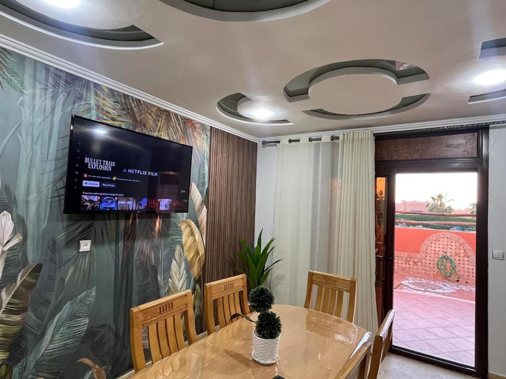 d'une salle à manger avec une table et une télévision murale. dans l'établissement Mini-villa Imiouadar vue mer , grand confort, à Agadir