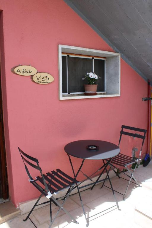 a table and two chairs next to a wall with a window at La bella vista in Conocchia