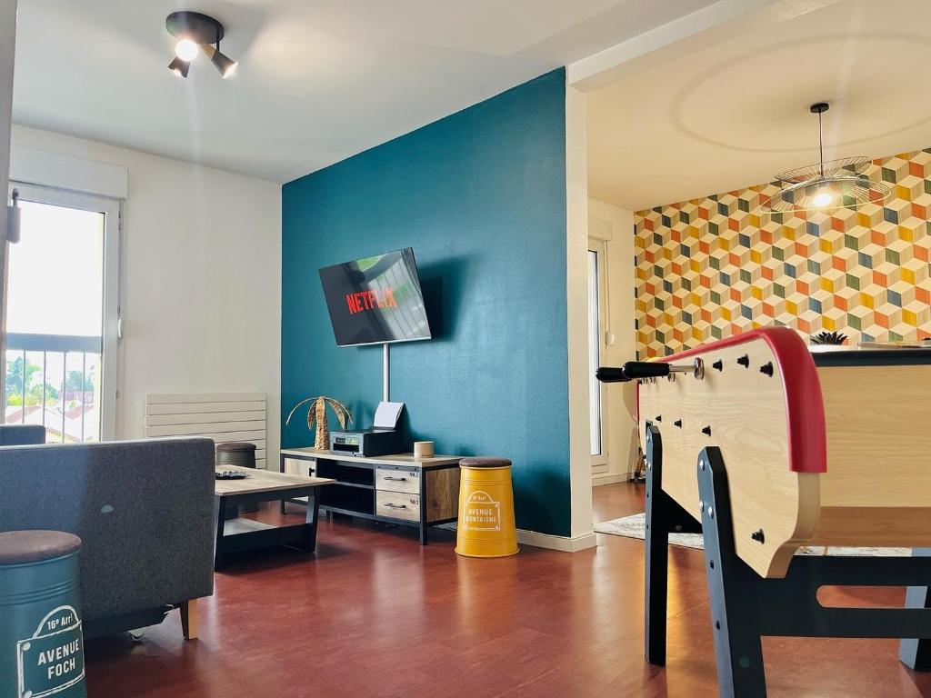 un salon avec une table et un mur bleu dans l'établissement Grand appart 4 chambres, à Épinal