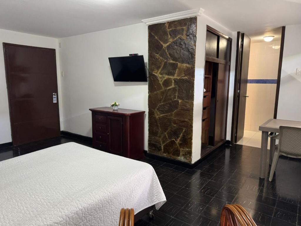 um quarto de hotel com uma cama e uma parede de pedra em Vallclaire Suites em Barranquilla
