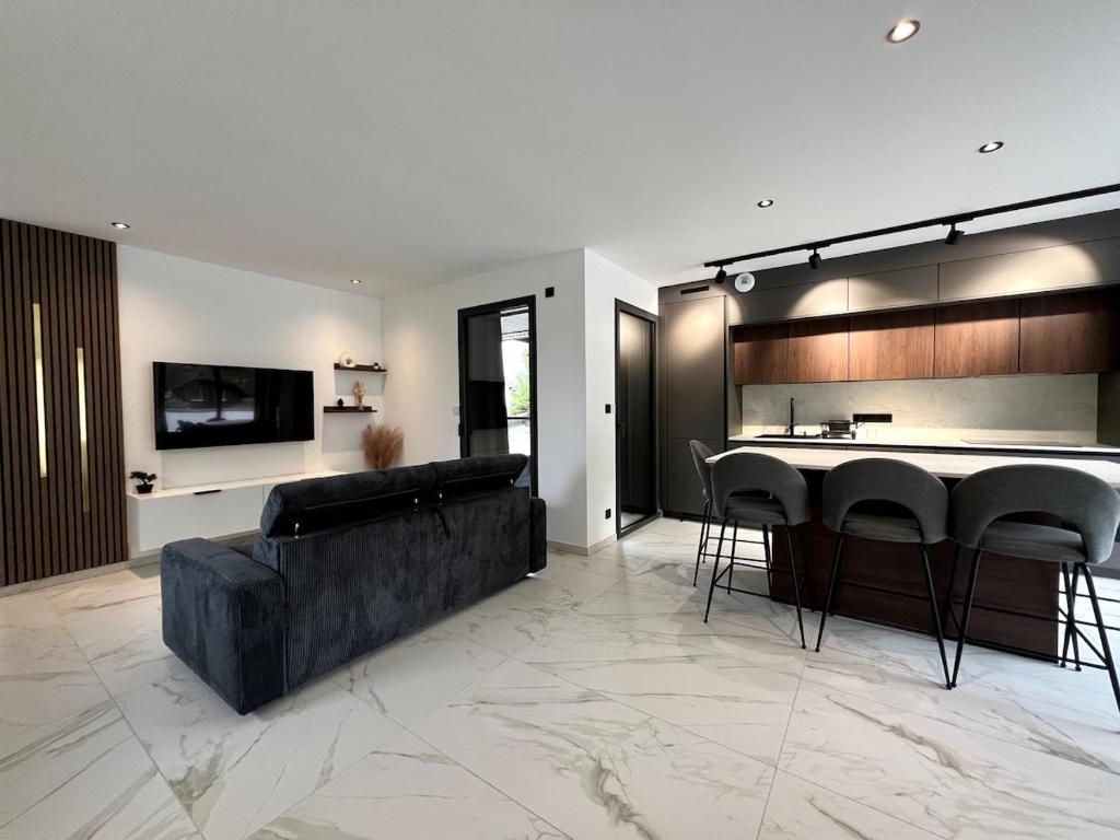 un salon avec un canapé noir et une cuisine dans l'établissement Appartement 2chambres entre lac et montagnes, à Sévrier