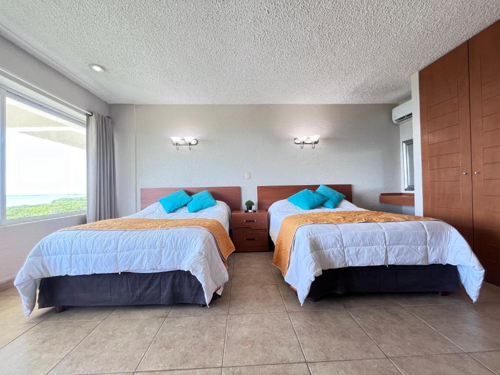una camera da letto con due letti con cuscini blu di Espacioso condo en Cancun - con acceso a playa a Cancún